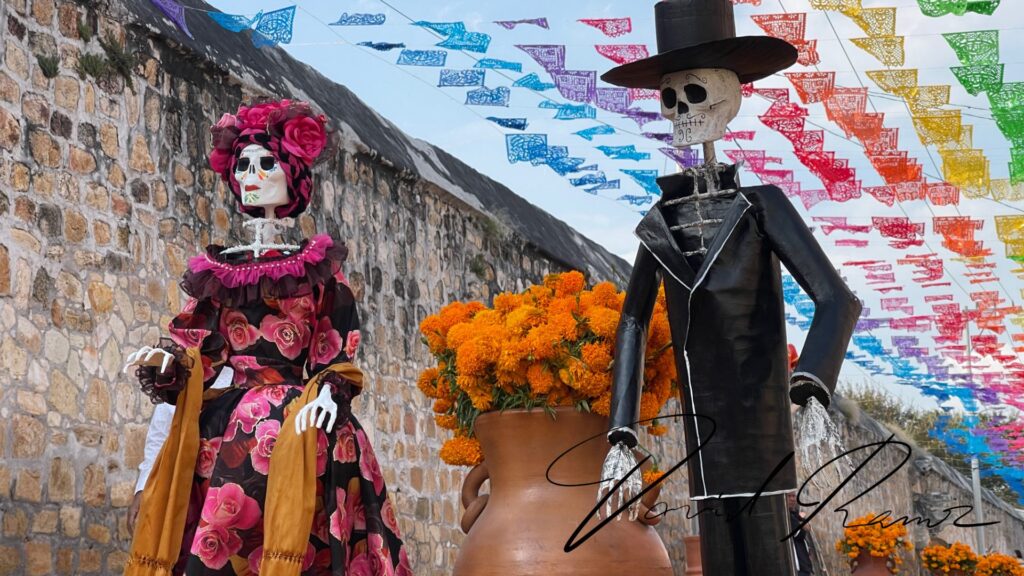 Catrina y catrín gigantes con papel picado y macetas de cempasúchil en Huaquechula, Puebla